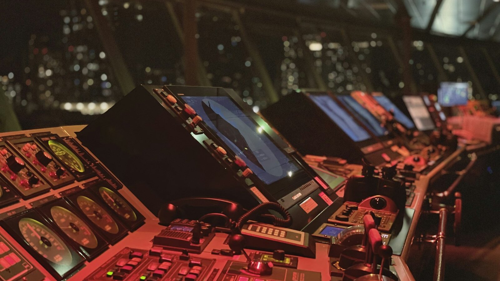 A ship navigation bridge filled with illuminated controls and monitoring screens